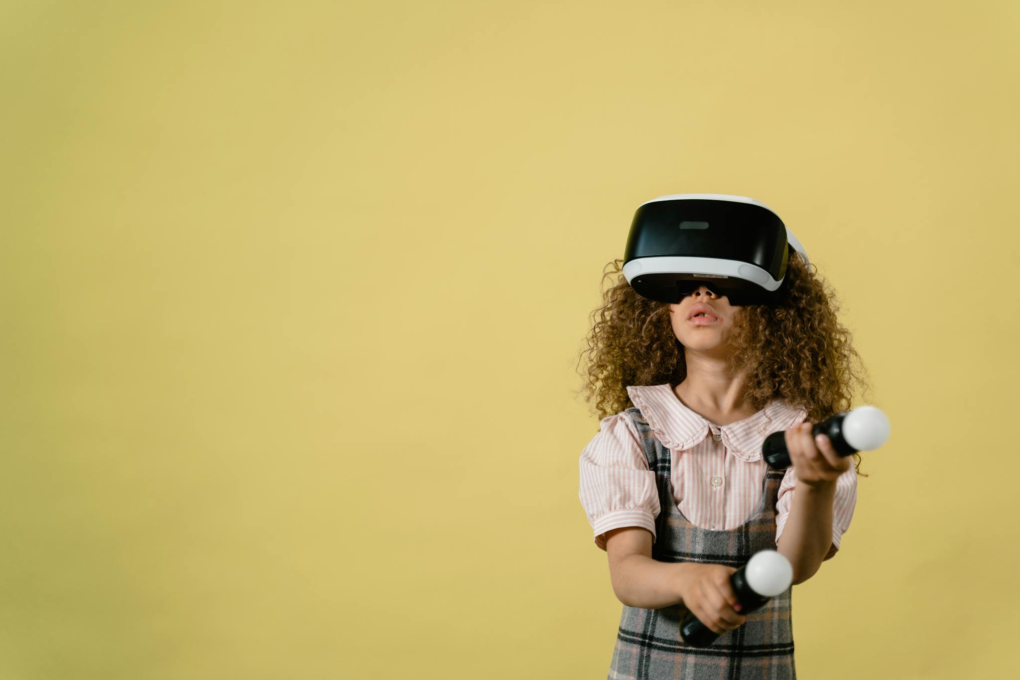 Curly-haired girl wearing VR headset and controllers, exploring virtual reality.