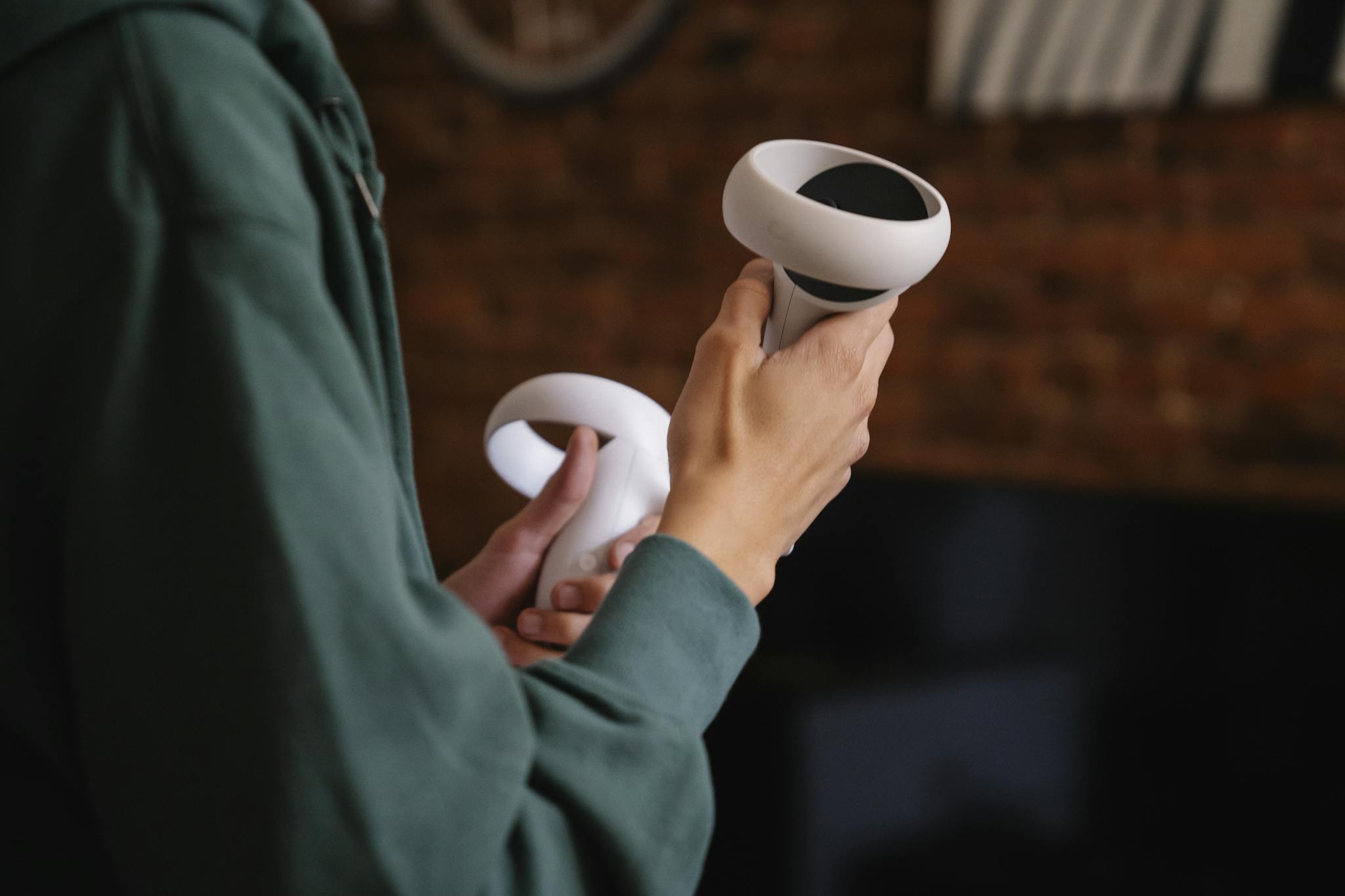 Side view of crop anonymous person with virtual reality controllers playing video game at home in daylight